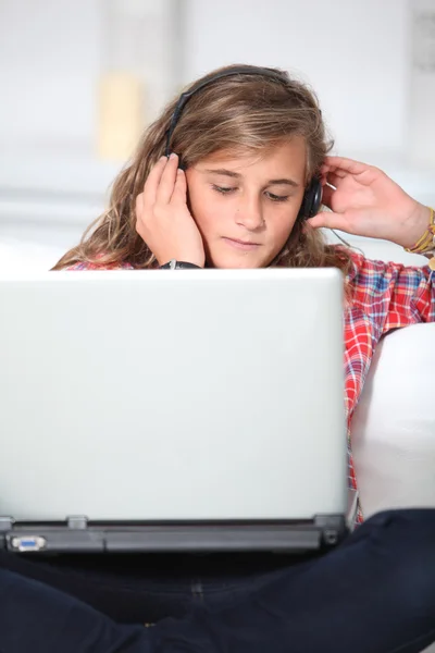 Tiener wth hoofdtelefoons en laptopcomputer — Stockfoto