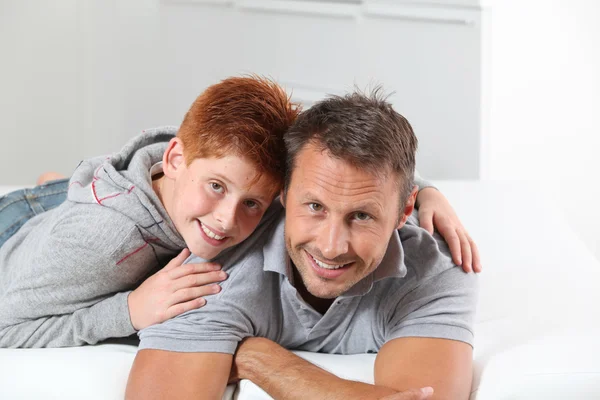 Man with child lying on a sofa at home Stock Image