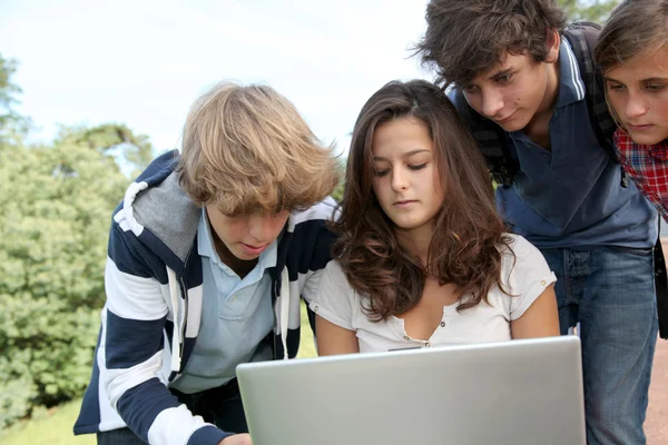 Adolescentes sentados afuera con computadora portátil Imágenes De Stock Sin Royalties Gratis