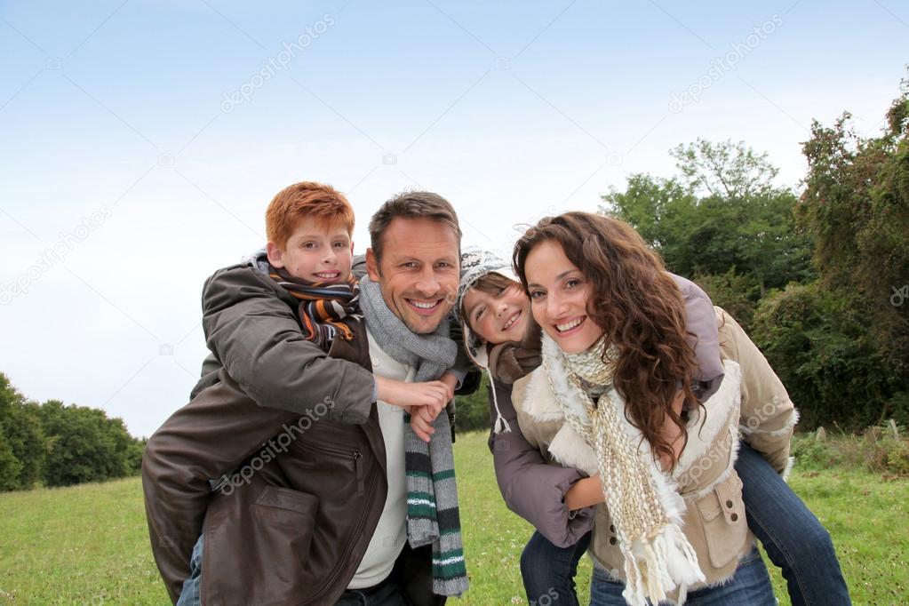 Parents doing piggyback to their children in countryside