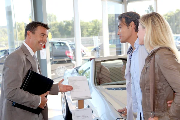 Car seller with couple in car dealership — Stock Photo, Image