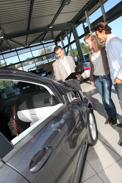 Carro vendedor com casal no showroom — Fotografia de Stock