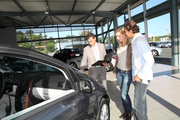 Car seller with couple in showroom — Stock Photo, Image