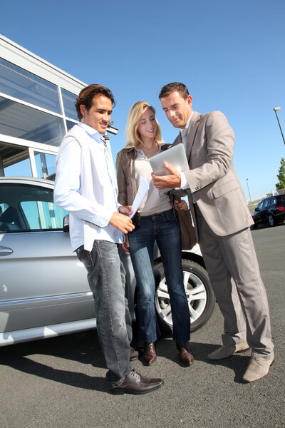 Car seller with couple looking at electronic tablet