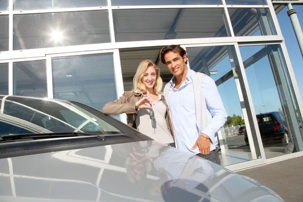 Couple holding car key in automobile dealership — Stock Photo, Image