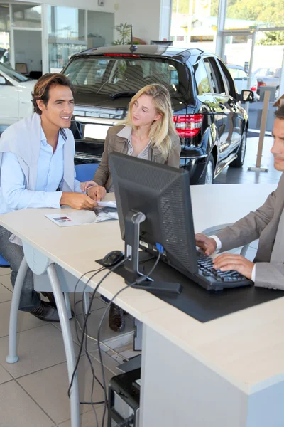 Car seller and couple of buyers signing contract — Stock Photo, Image