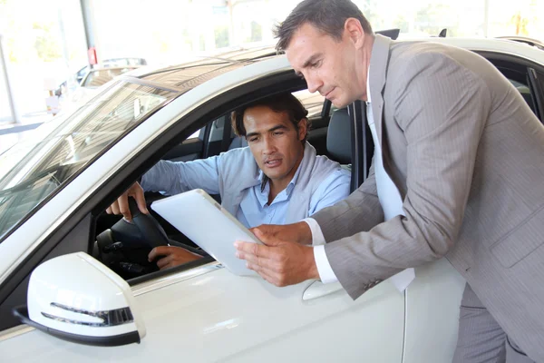 Car seller with car buyer looking at electronic tablet — Stock Photo, Image