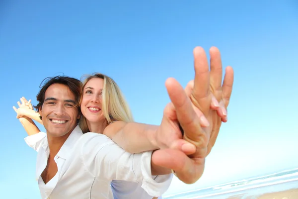 Lyckliga paret sträcker armarna på stranden — Stockfoto