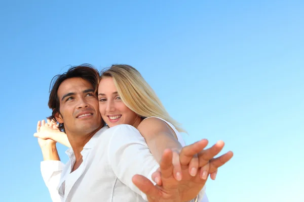 Lyckliga paret sträcker armarna på stranden — Stockfoto