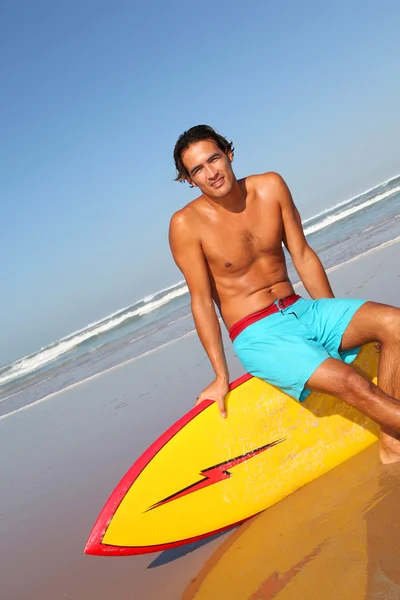 Handsome man sitting on his surfboard — Stock Photo, Image