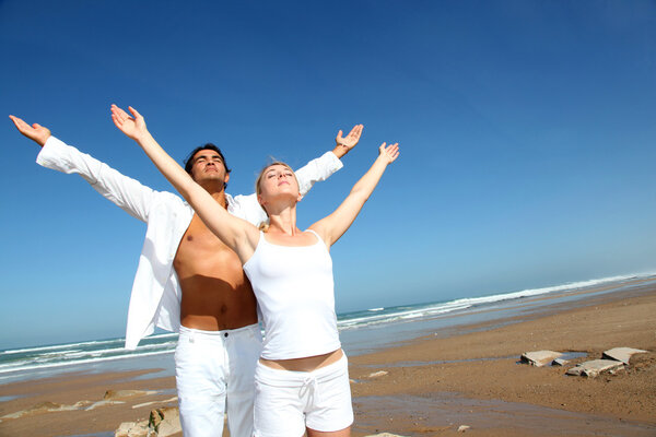 Couple doing yoga exercises on the beach