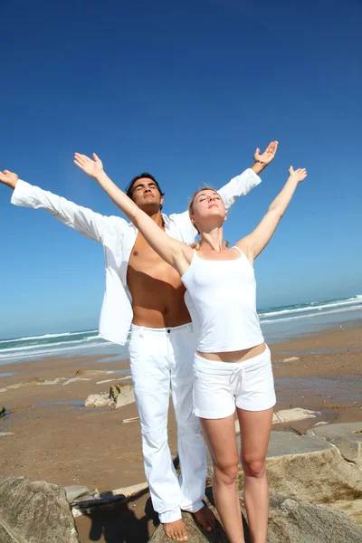 Par gör yogaövningar på stranden — Stockfoto