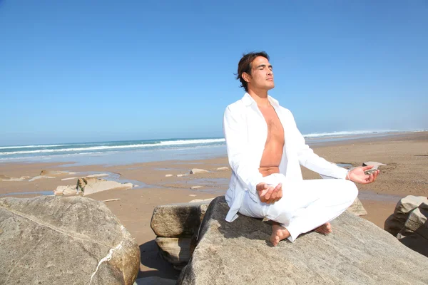 Мужчина делает медитационные упражнения на пляже — стоковое фото