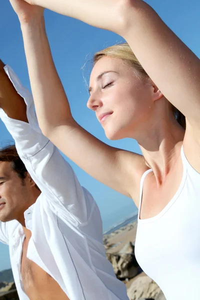 Couple faisant des exercices de yoga sur la plage — Photo