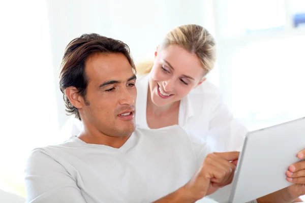 Jeune couple utilisant une tablette électronique à la maison — Photo