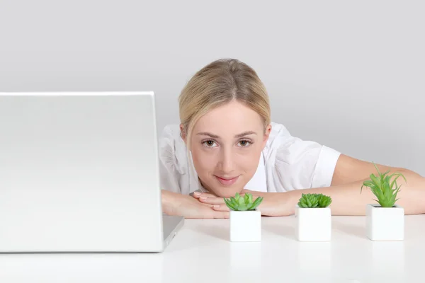 Mulher loira sentado por computador e plantas verdes — Fotografia de Stock