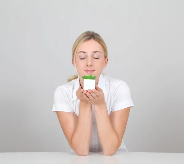 Beautiful blond woman smelling green plant — Stock Photo, Image