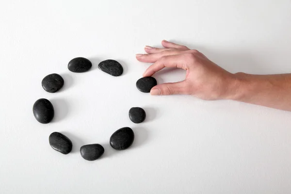 Human hand arranging line of pebbles in circle — Stock Photo, Image