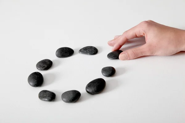 Human hand arranging line of pebbles in circle — Stock Photo, Image