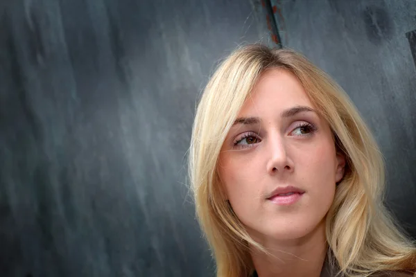 Blond woman leaning on black wall — Stock Photo, Image