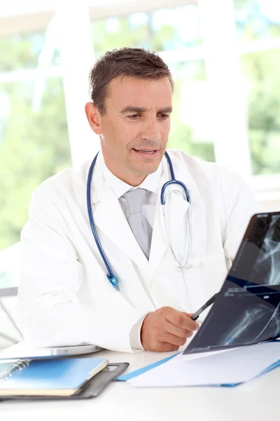 Портрет улыбающегося доктора, смотрящего на рентген — стоковое фото