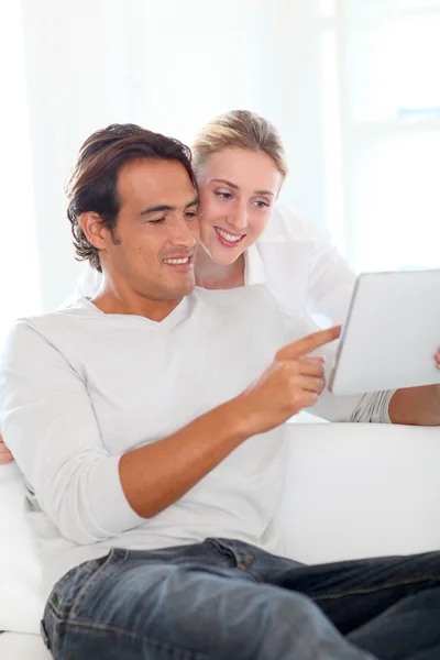 Ungt par som bruker nettbrett hjemme stockbilde