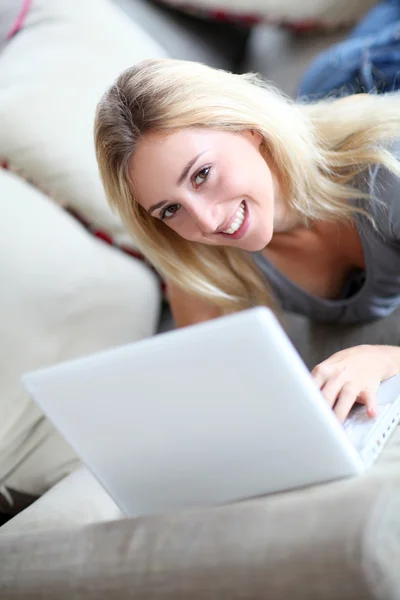 Mädchen liegt mit Laptop auf Sofa Stockbild