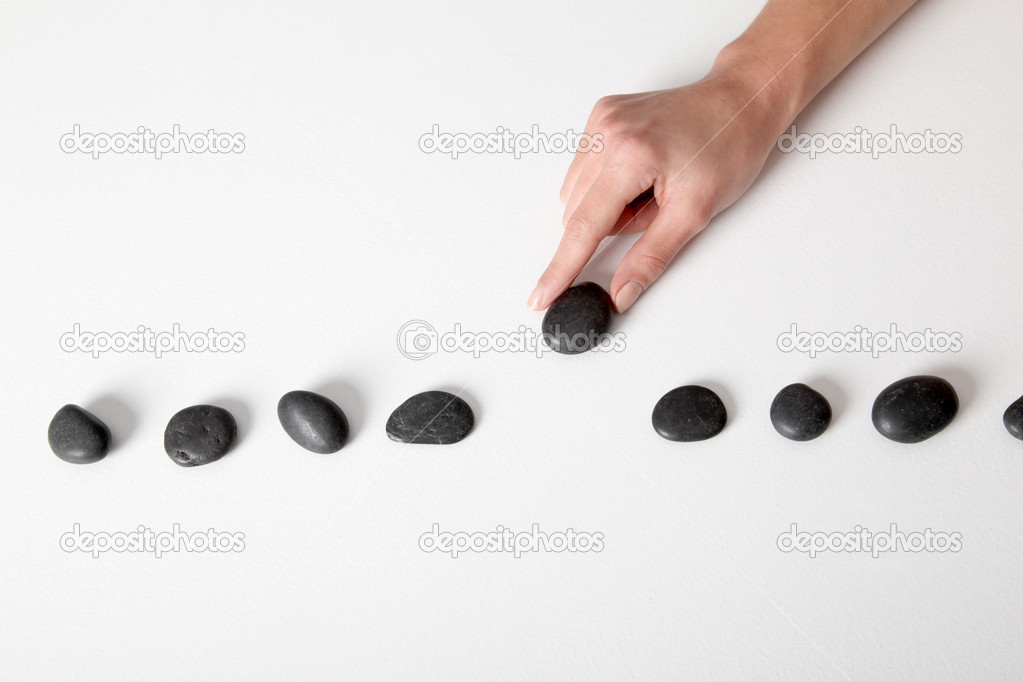 Human hand arranging line of pebbles