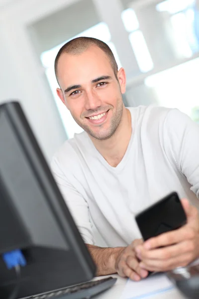 Uśmiechający się pracownik biurowy, siedząc przed komputerem stacjonarnym — Zdjęcie stockowe