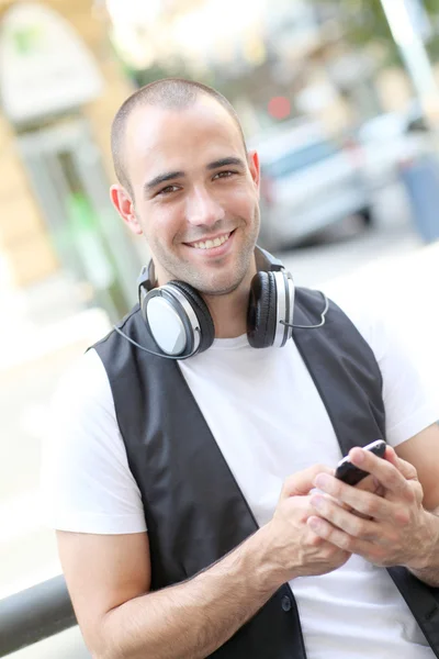 Uomo sorridente che ascolta musica per strada — Foto Stock