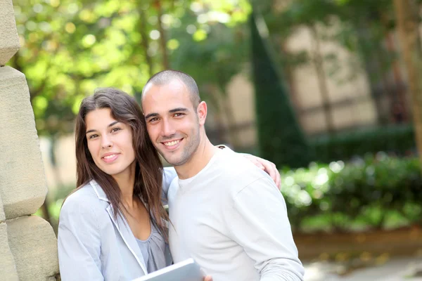 Pareja joven en parque público con tableta electrónica — Foto de Stock