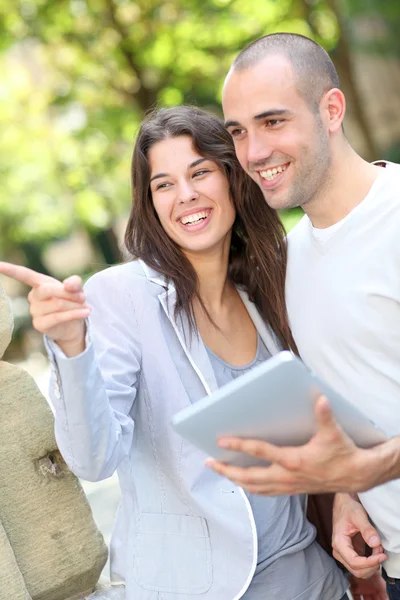 Coppia giovane nel parco pubblico con tablet elettronico — Foto Stock