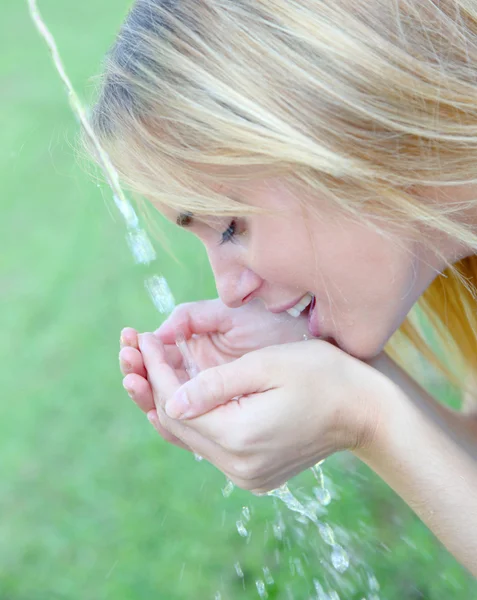 Mujer joven bebiendo agua de la fuente — Foto de Stock