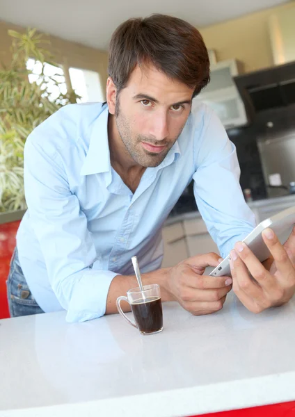 Человек, стоящий на кухне с электронным планшетом — стоковое фото