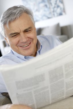 Senior hombre sonriendo como leer el periódico