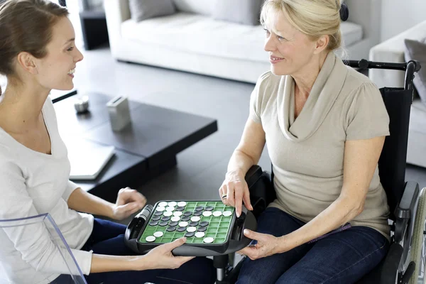 Young homecarer playing game with elderly woman — Stock Photo, Image
