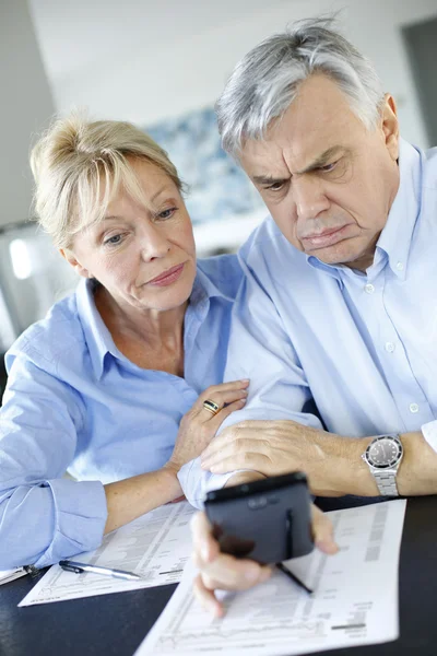 Äldre par calculting räkningar belopp med smartphone — Stockfoto