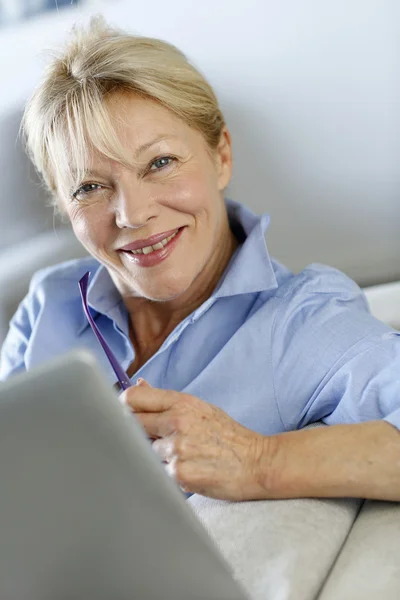 Mujer mayor usando tableta electrónica en sofá — Foto de Stock