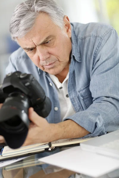 Photographer in office looking at camera screen — Stock Photo, Image