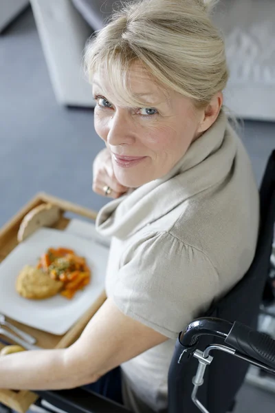 Senior vrouw in rolstoel houdt lunch lade — Stockfoto