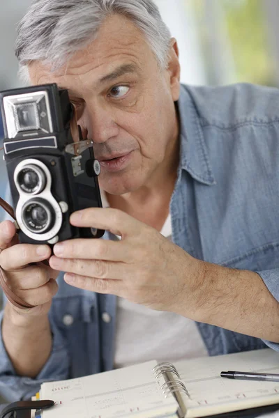 Старший фотограф держит винтажную камеру — стоковое фото