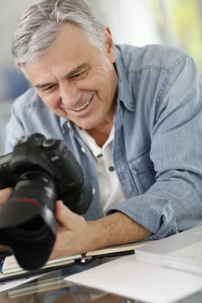 Photographer in office looking at camera screen — Stock Photo, Image