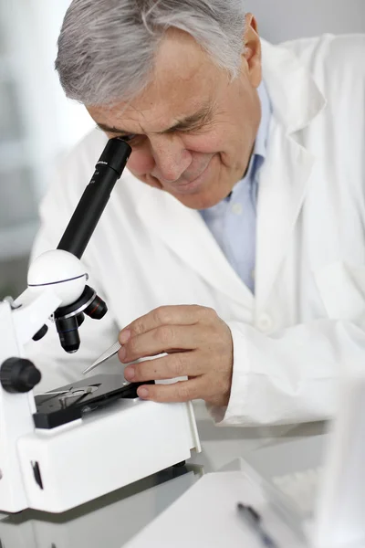 Вчений в лабораторії, який дивиться через лінзу мікроскопа — стокове фото