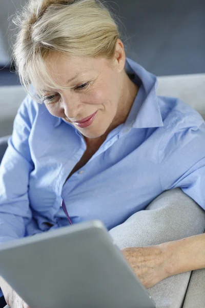 Donna anziana che utilizza tablet elettronico in divano — Foto Stock