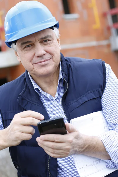 Entreprenör på byggarbetsplats med smartphone — Stockfoto