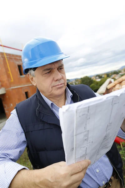 Gerente de construcción verificando proyecto de construcción en sitio — Foto de Stock