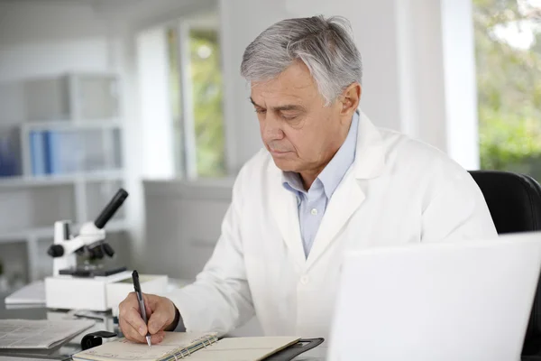 Doctor en biología escribiendo informe sobre agenda — Foto de Stock