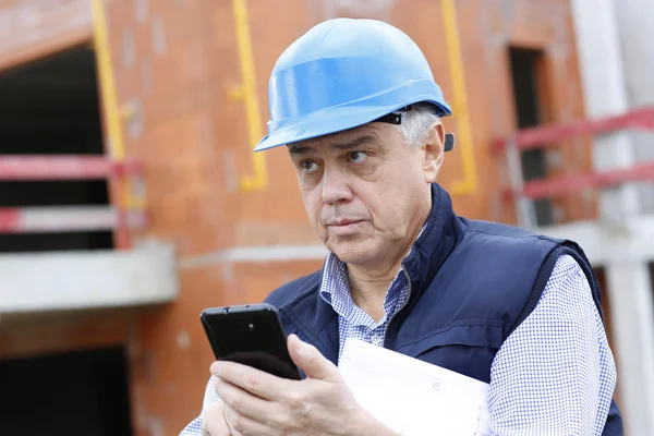 Empreendedor no local de construção usando smartphone — Fotografia de Stock