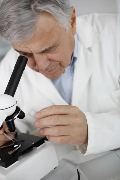 Scientist in lab looking through microscope lens — Stock Photo, Image
