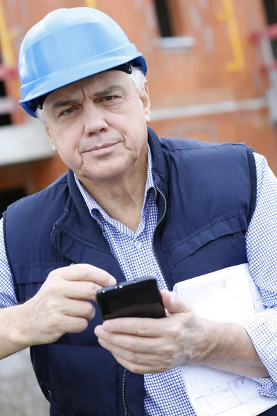 Empreendedor no local de construção usando smartphone — Fotografia de Stock